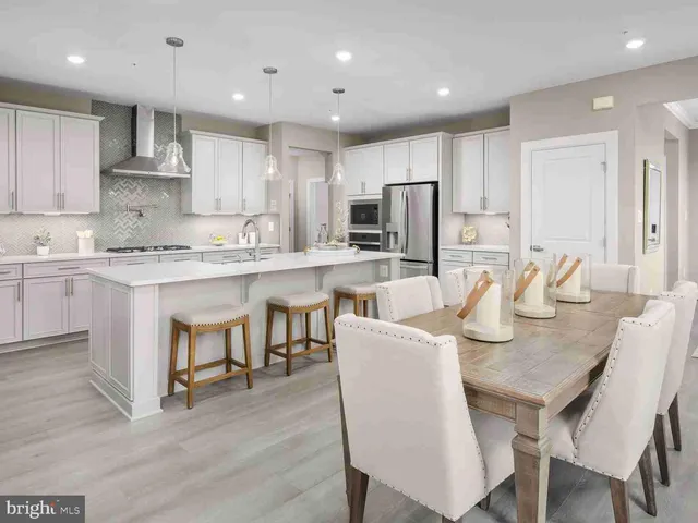 a kitchen with stainless steel appliances granite countertop a dining table chairs refrigerator microwave and cabinets