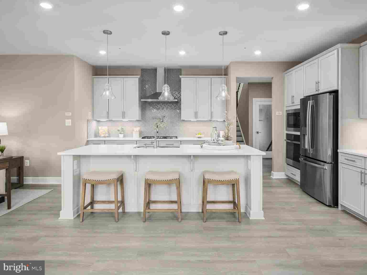 6558 Stream Song Court Columbia, MD 21044 - Photo 7 of 20 a kitchen with stainless steel appliances granite countertop a white cabinets and wooden floor