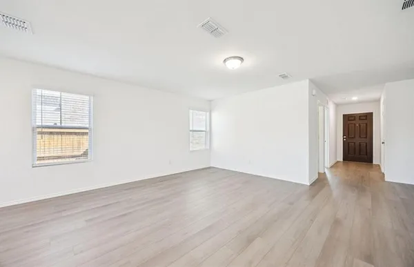 an empty room with wooden floor and windows