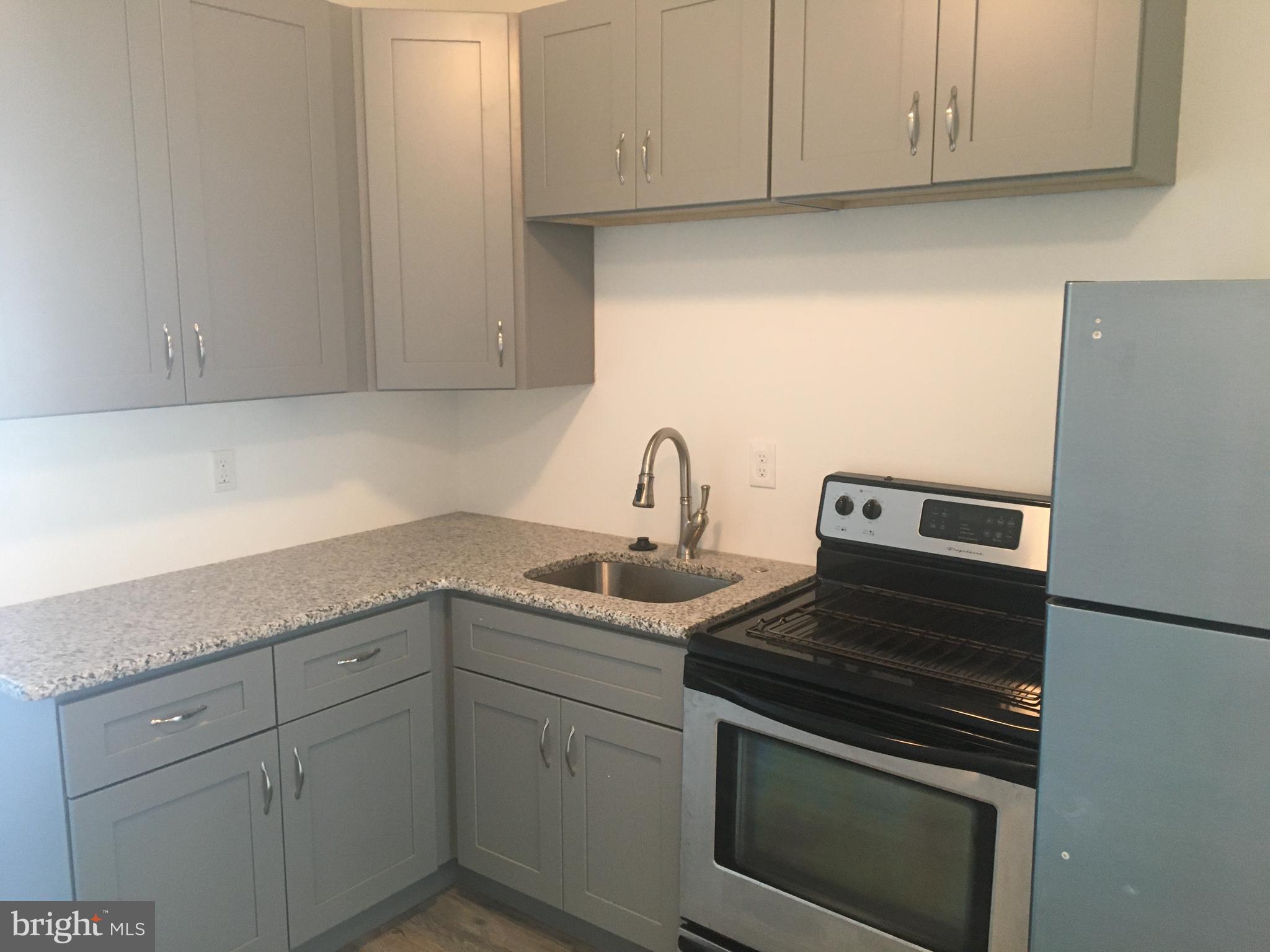 1908 Darby Road, Unit 2 Havertown, PA 19083 - Photo 4 of 14 a kitchen with stainless steel appliances granite countertop white cabinets and a stove top oven