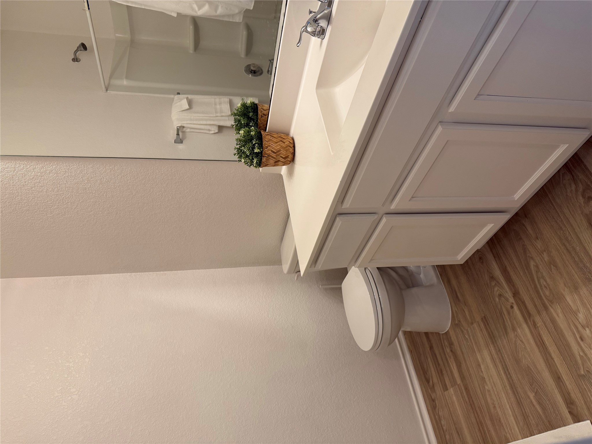 14907 Retha Pass Austin, TX 78725 - Photo 3 of 22 A pristine bath showcasing wood-look flooring and a functional vanity with a sleek sink.