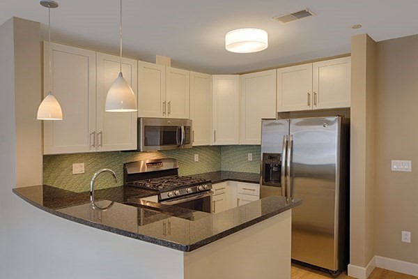 a kitchen with stainless steel appliances granite countertop a refrigerator a stove a sink and a white cabinets