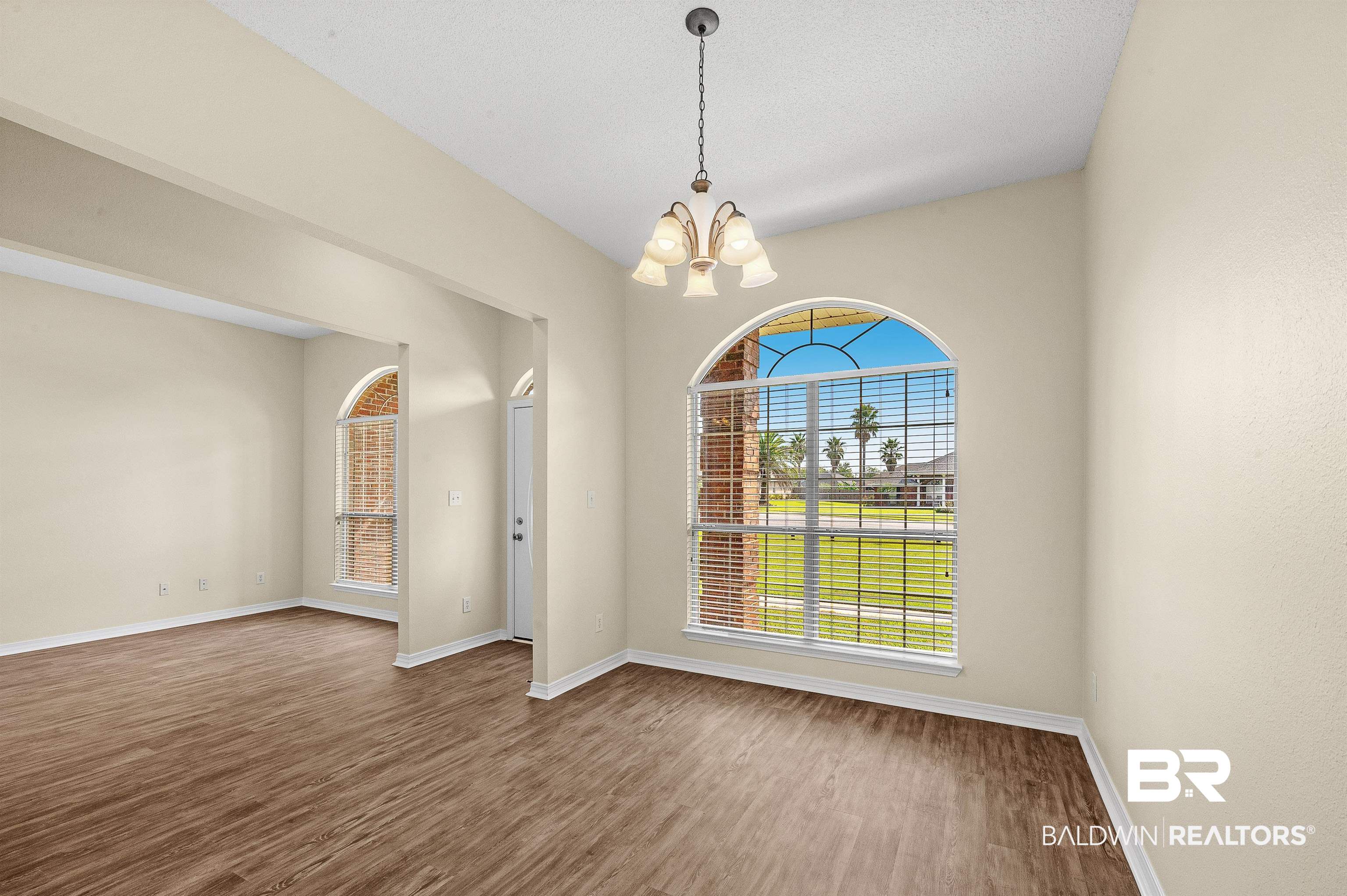 12443 Venice Boulevard Foley, AL 36535 - Photo 12 of 59 Empty room with hardwood / wood-style flooring and a notable chandelier
