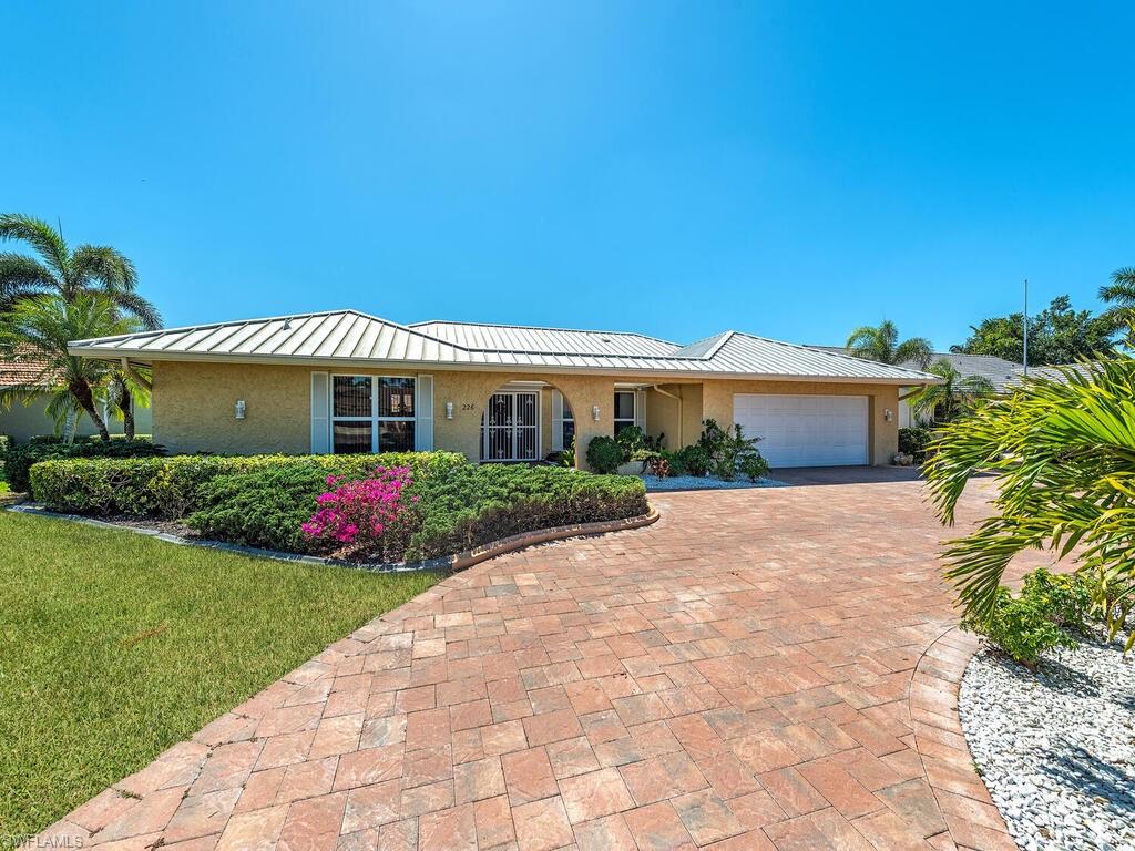 226 Torrey Pines Point Naples, FL 34113 - Photo 1 of 27 Single story home with decorative driveway, a front yard, stucco siding, and an attached garage
