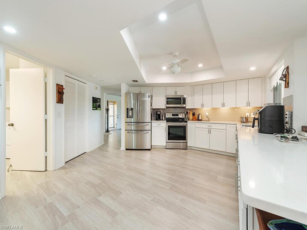 226 Torrey Pines Point Naples, FL 34113 - Photo 13 of 27 Kitchen with light countertops, backsplash, a raised ceiling, appliances with stainless steel finishes, and ceiling fan
