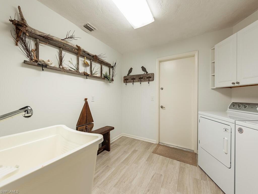 226 Torrey Pines Point Naples, FL 34113 - Photo 21 of 27 Laundry room featuring a sink, separate washer and dryer, light wood-style flooring, visible vents, and cabinet space