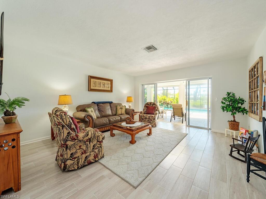 226 Torrey Pines Point Naples, FL 34113 - Photo 7 of 27 Living area featuring a textured ceiling, baseboards, light wood-style flooring, and visible vents