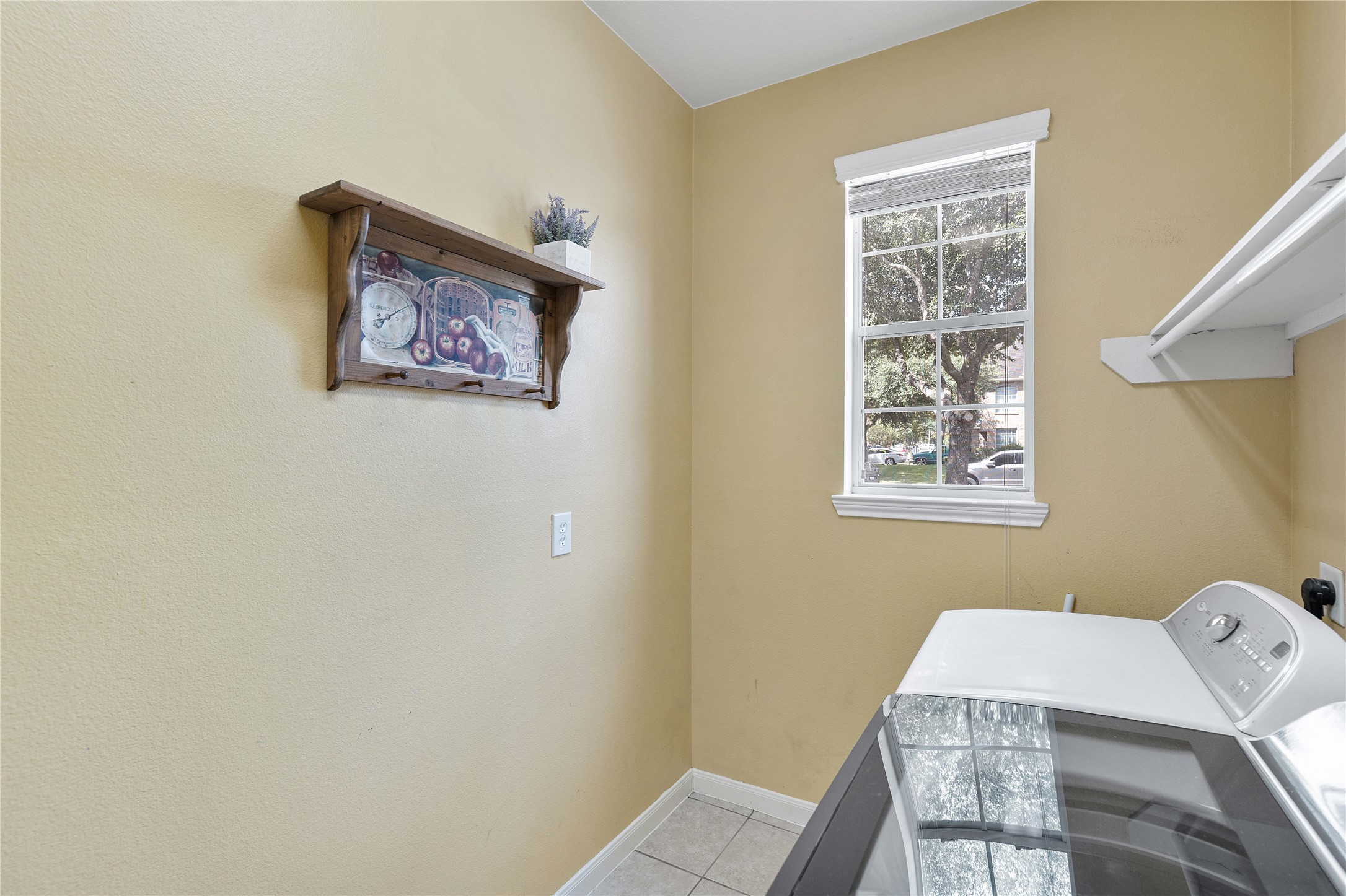 24506 Fort Path Drive Spring, TX 77373 - Photo 25 of 46 Bright laundry room with a window, featuring a washer, dryer, and wall-mounted shelf for added storage.