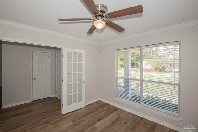 a view of an empty room with wooden floor and a window