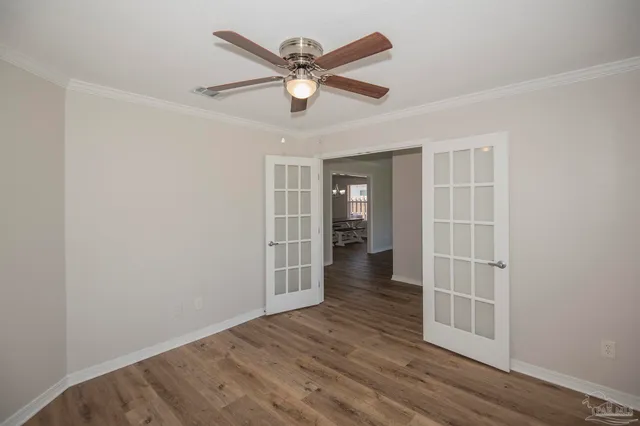 an empty room with wooden floor and ceiling fan