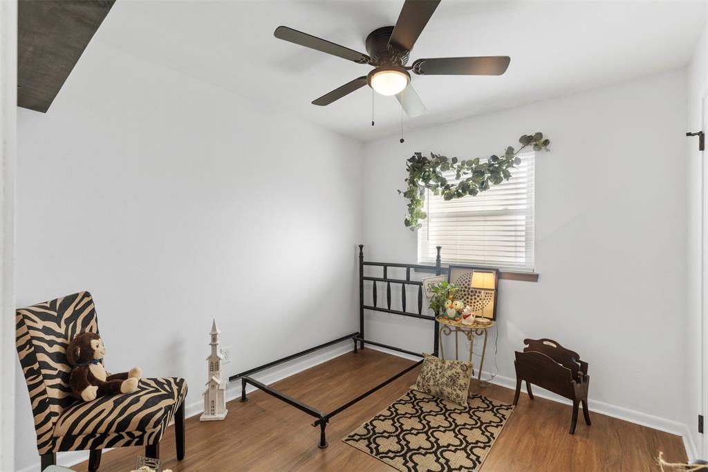 708 East Prairie View Road Crowley, TX 76036 - Photo 10 of 21 White walls featuring wood-finish flooring, a window with horizontal blinds, and a dark-toned ceiling fan