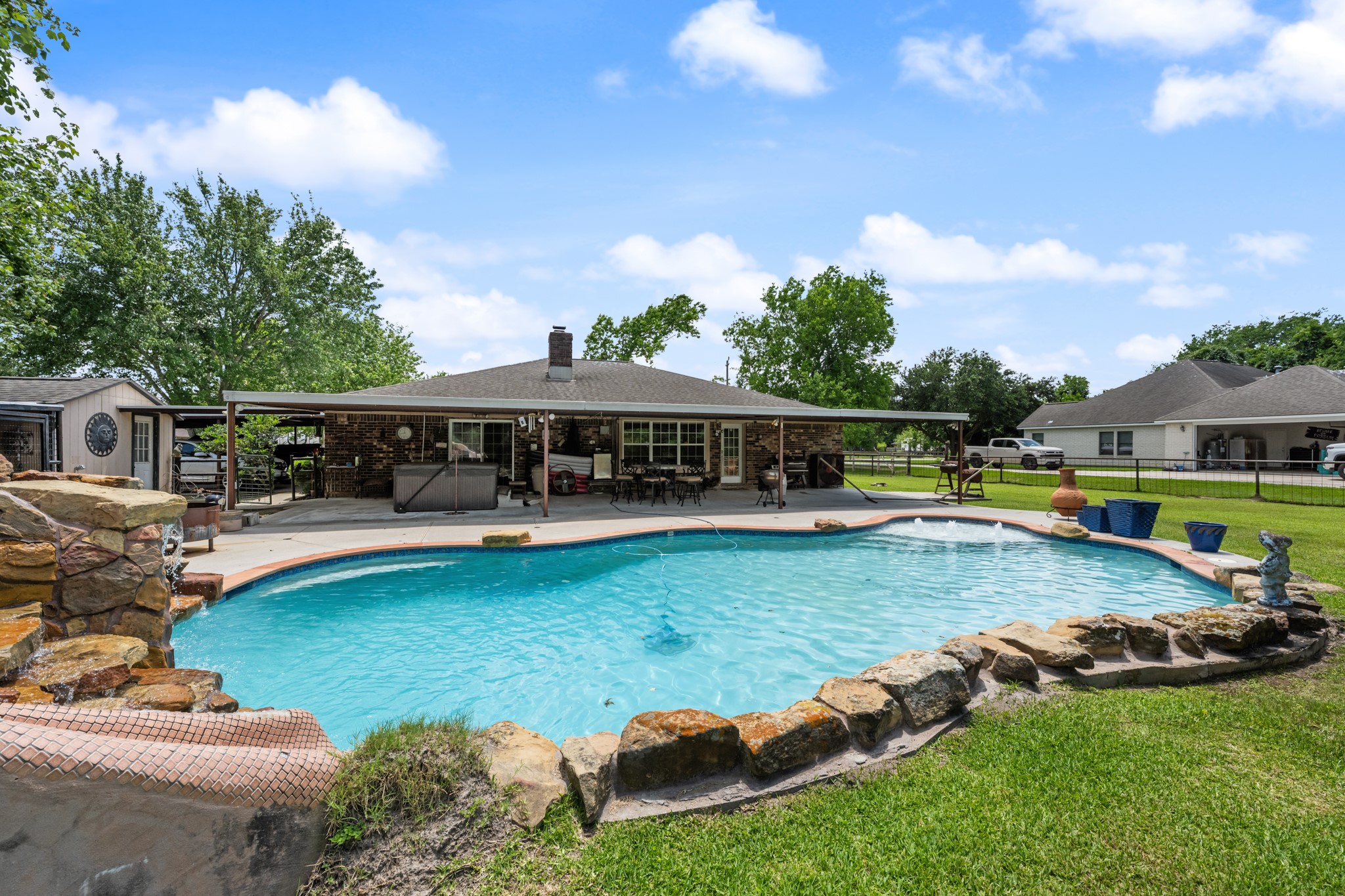15602 Fir Road Santa Fe, TX 77517 - Photo 30 of 42 Spacious backyard oasis featuring a resort-style pool with a custom rock waterfall slide, expansive green space, and a large covered patio perfect for outdoor entertaining and relaxing year-round.