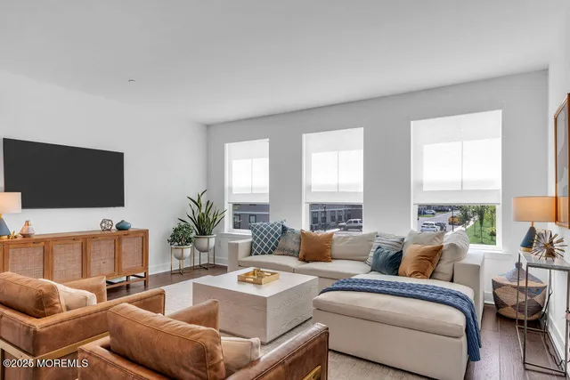 a large white kitchen with lots of counter space a sink appliances and living room view