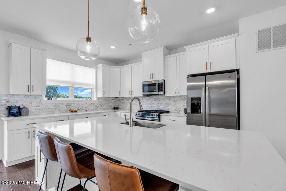 63 Bataan Avenue Tinton Falls, NJ 07724 - Photo 21 of 64 a kitchen with stainless steel appliances granite countertop a sink a stove a refrigerator cabinets and chairs