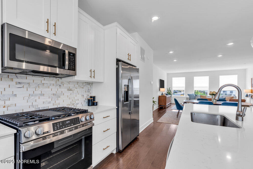 63 Bataan Avenue Tinton Falls, NJ 07724 - Photo 23 of 64 a kitchen with stainless steel appliances a stove microwave and sink