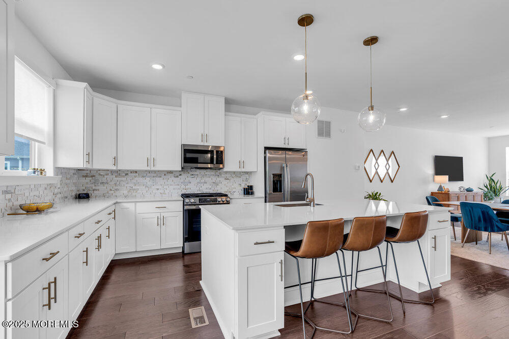 63 Bataan Avenue Tinton Falls, NJ 07724 - Photo 25 of 64 a kitchen with stainless steel appliances kitchen island granite countertop a refrigerator a stove a sink a dining table and chairs with wooden floor