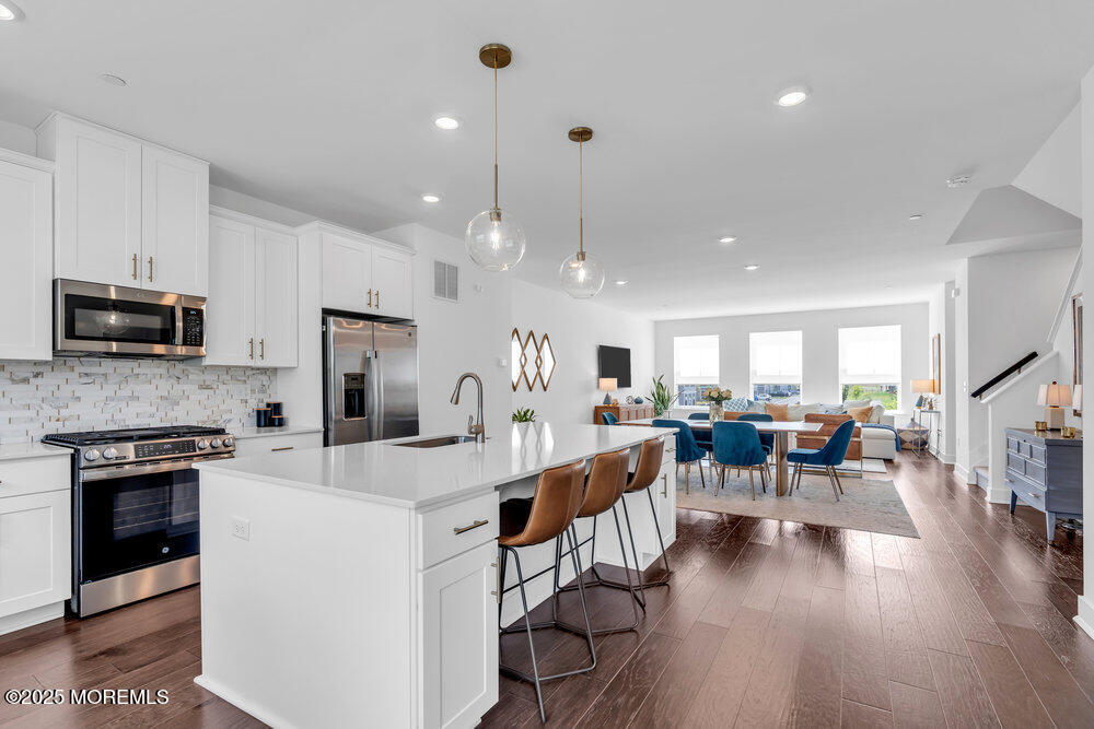 63 Bataan Avenue Tinton Falls, NJ 07724 - Photo 26 of 64 a large white kitchen with lots of counter space a sink appliances and living room view