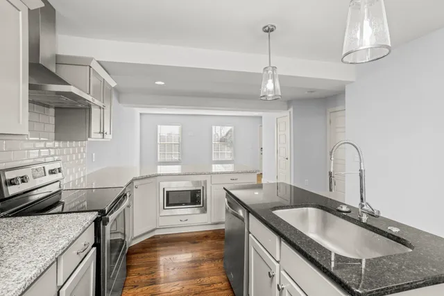 a kitchen with granite countertop stainless steel appliances a sink stove and cabinets