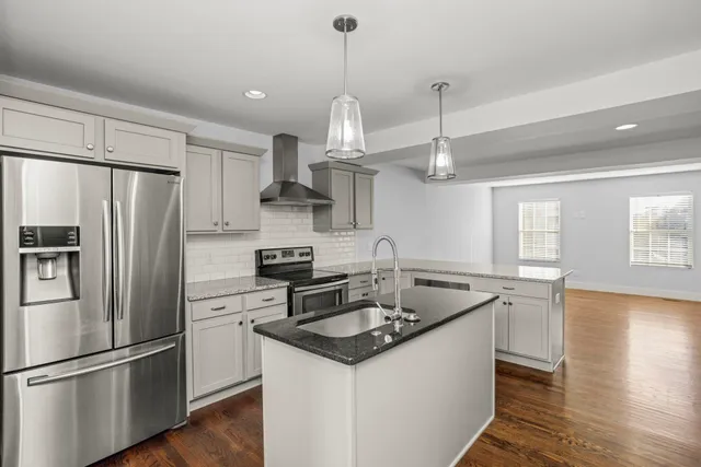 a kitchen with stainless steel appliances granite countertop a sink stove a refrigerator and a refrigerator