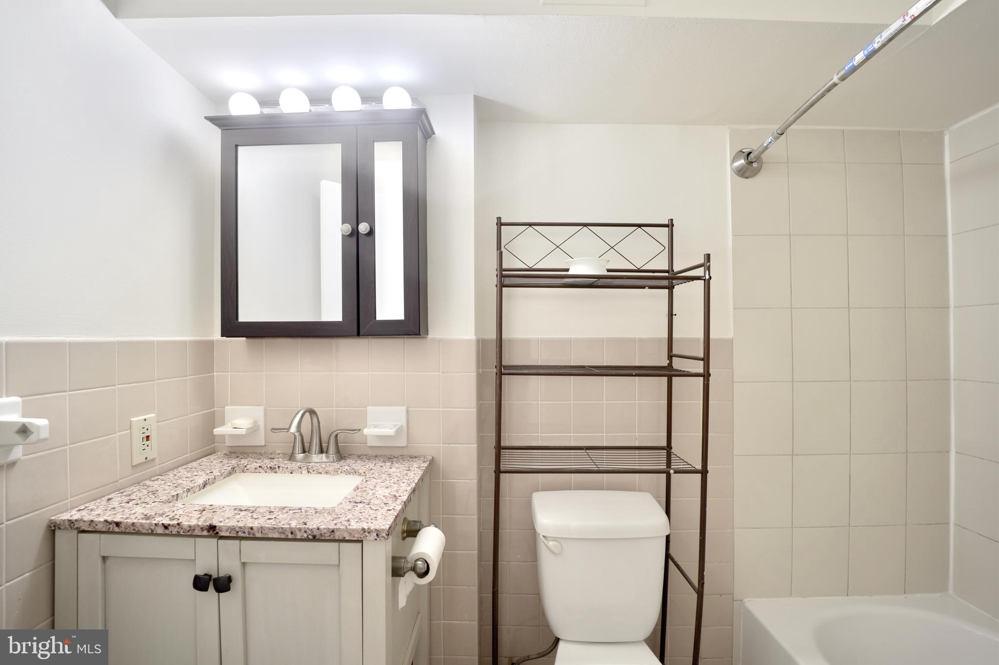 1926 15th Street Northwest, Unit 1 Washington, DC 20009 - Photo 8 of 13 a bathroom with a granite countertop sink toilet and shower