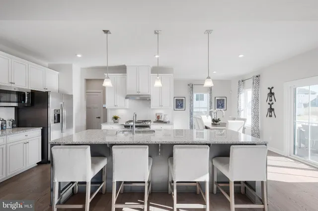 a large kitchen with kitchen island a dining table chairs and white cabinets