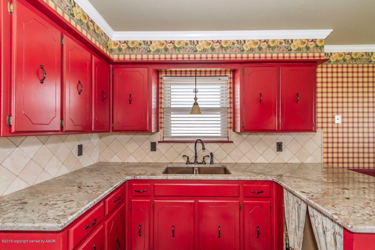 5337 Whitney Lane Amarillo, TX 79110 - Photo 15 of 32 a kitchen with stainless steel appliances granite countertop a red stove top oven a sink dishwasher and wooden cabinets