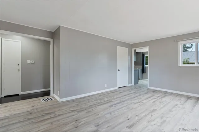 a view of an empty room with wooden floor and closet