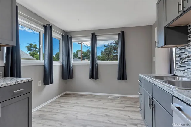 a kitchen with stainless steel appliances granite countertop a sink a stove and a wooden cabinets