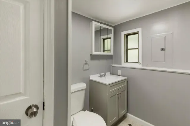 a bathroom with a toilet sink vanity and mirror