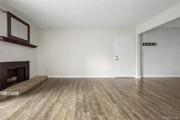 a view of empty room with wooden floor and fireplace