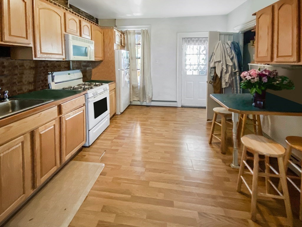 363 West 3rd Street, Unit 1 Boston, MA 02127 - Photo 6 of 12 a kitchen with stainless steel appliances granite countertop a stove top oven a sink dishwasher and a dining table with wooden floor