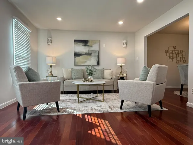 a living room with couches and a dining table with wooden floor