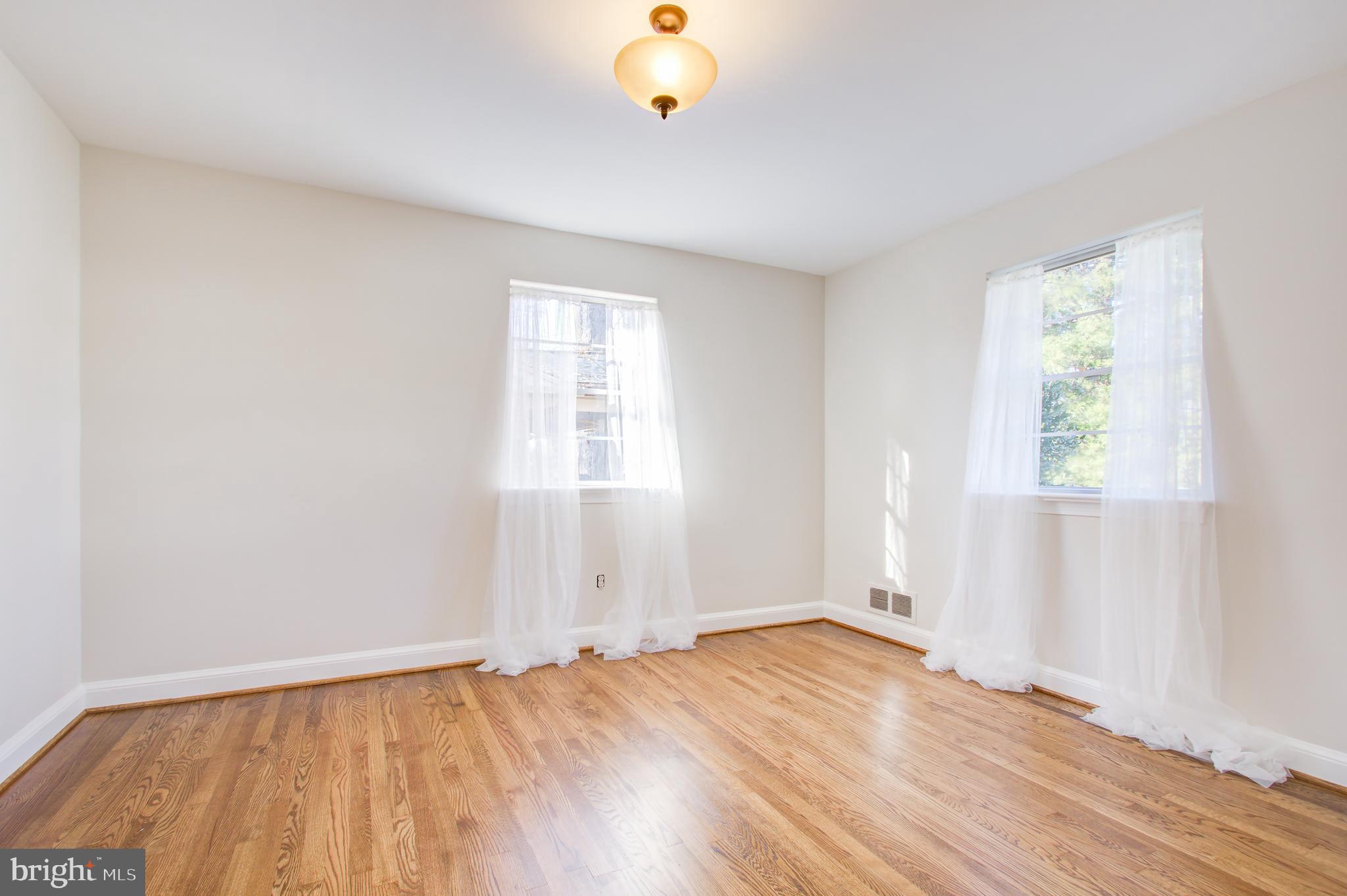 1004 Stirling Road Silver Spring, MD 20901 - Photo 17 of 27 an empty room with wooden floor and windows