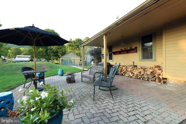 a view of a patio with table and chairs under an umbrella with a fire pit and potted plants