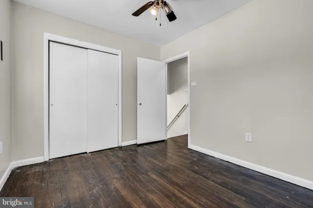 an empty room with wooden floor chandelier fan and windows