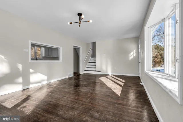 a view of an empty room with a window and wooden floor