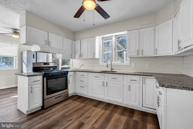 a kitchen with granite countertop white cabinets white stainless steel appliances and sink