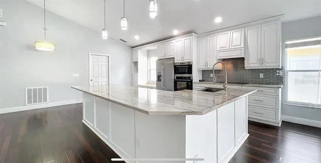 a kitchen with kitchen island granite countertop a sink appliances cabinets and a counter top space