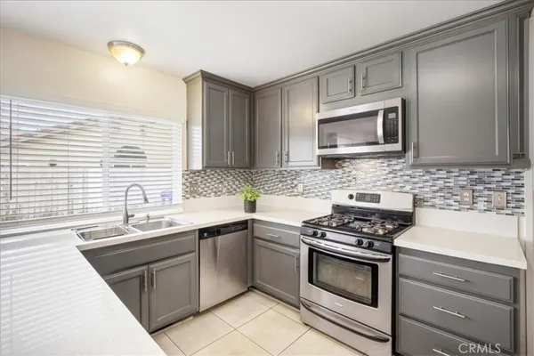 a kitchen with cabinets stainless steel appliances a sink and a window
