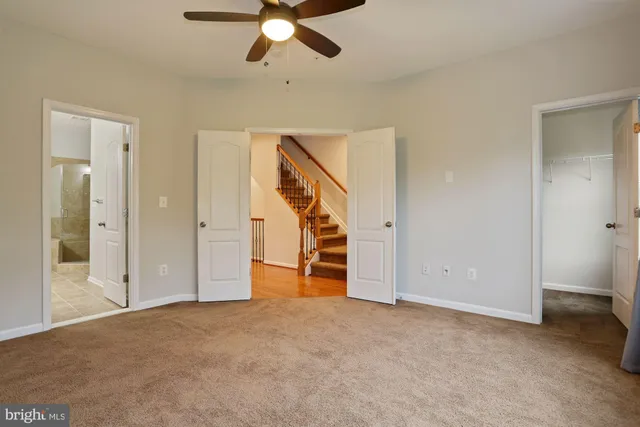 an empty room with chandelier fan and entryway
