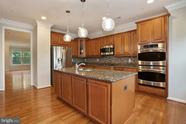 a kitchen with stainless steel appliances granite countertop a sink a stove and a wooden floors