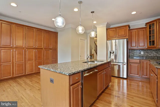 a kitchen with stainless steel appliances granite countertop a sink a stove and a wooden floors