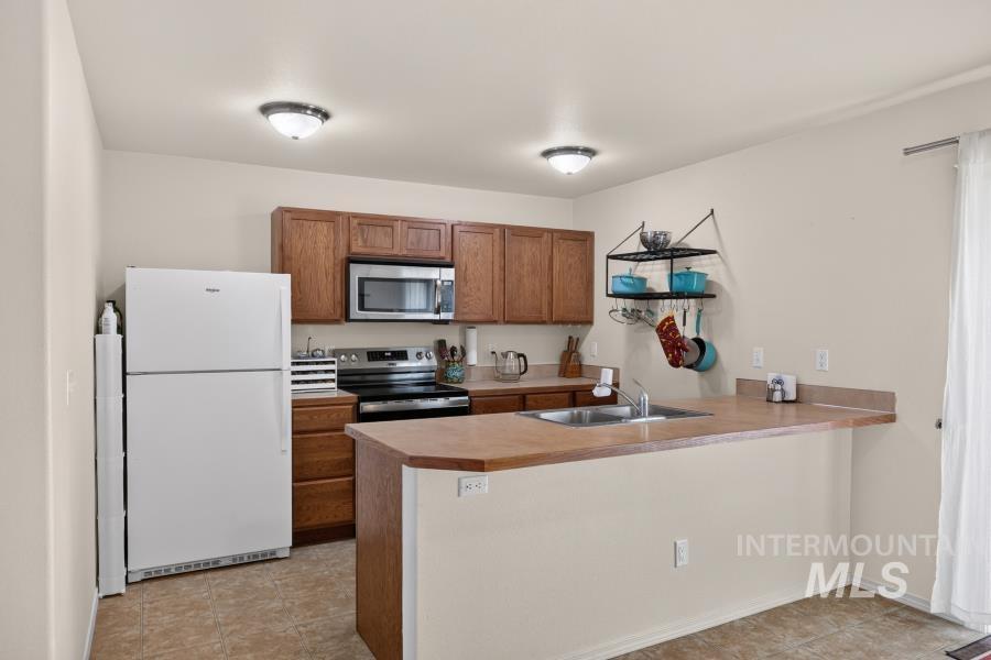 1337 Bristol Road Moscow, ID 83843 - Photo 10 of 28 Open-concept kitchen featuring wood cabinetry, stainless steel appliances, a breakfast bar, and tile flooring