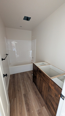 26063 North 8800th West Portage, UT 84331 - Photo 7 of 9 Contemporary bathroom featuring wood-finish flooring, a white subway tile tub surround, and a dark wood vanity base