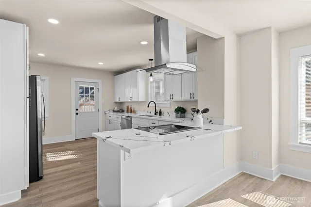 a view of a kitchen with kitchen island a sink stainless steel appliances and cabinets