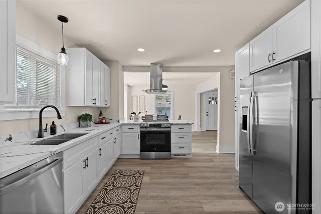 a large kitchen with stainless steel appliances kitchen island granite countertop a refrigerator and a sink