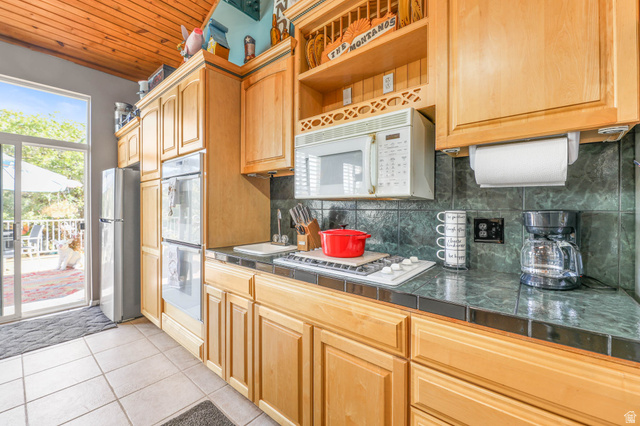 569 Elk Meadow Loop Tooele, UT 84074 - Photo 18 of 56 Kitchen with white appliances, tasteful backsplash, light tile patterned floors, wooden ceiling, and light wood finish cabinets