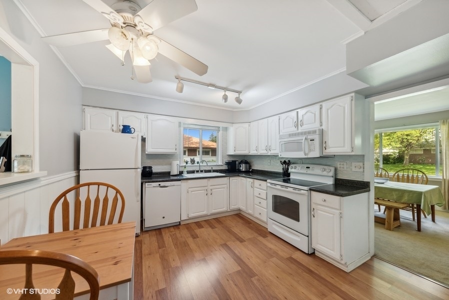14 Aldine Road Lake Zurich, IL 60047 - Photo 5 of 15 a kitchen with stainless steel appliances granite countertop a stove a sink dishwasher a microwave oven with a dining table and chairs with wooden floor