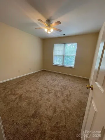 en empty room with windows and chandelier fan