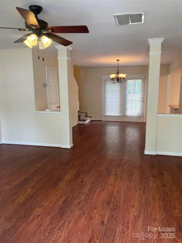 a view of an empty room with wooden floor and a ceiling fan